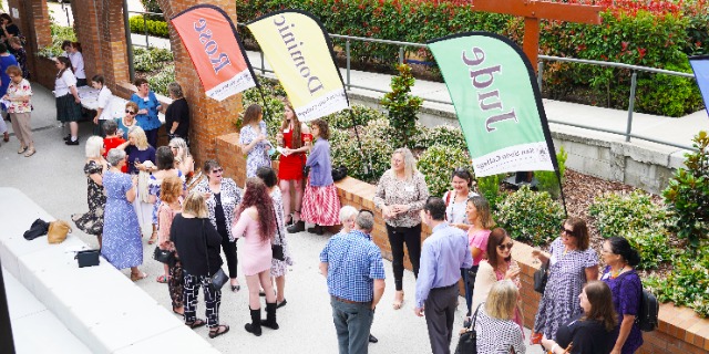 families and school community connecting outdoors during an event with welcome signage, emphasising engagement and relationships