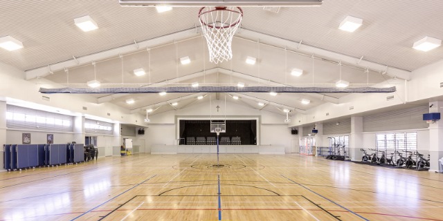 Indoor multipurpose sports hall with basketball court and equipment, supporting physical education and school sport