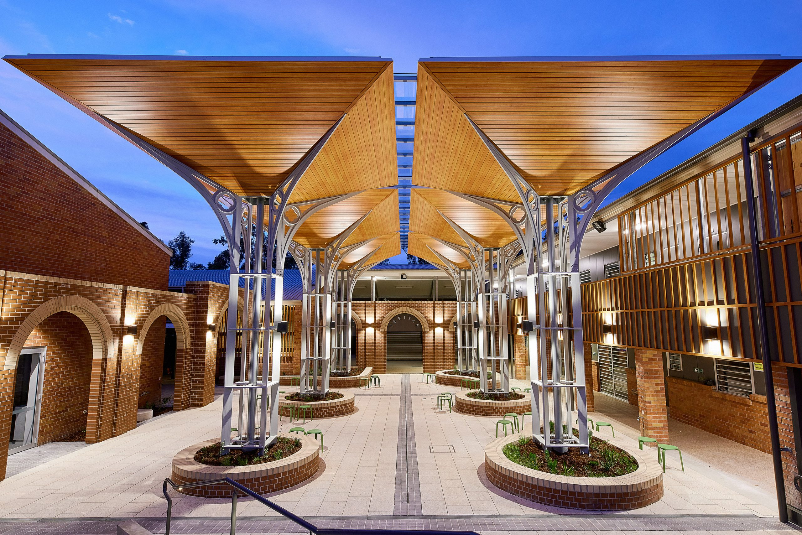 Modern courtyard with timber canopy structures and seating areas, highlighting contemporary learning spaces and a welcoming campus environment at San Sisto College